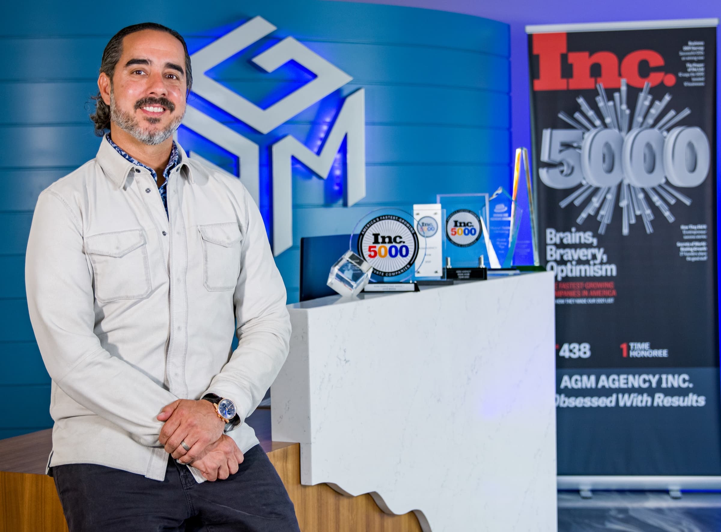 Manuel Suarez seated at a desk at AGM, looking straight at the camera and smiling