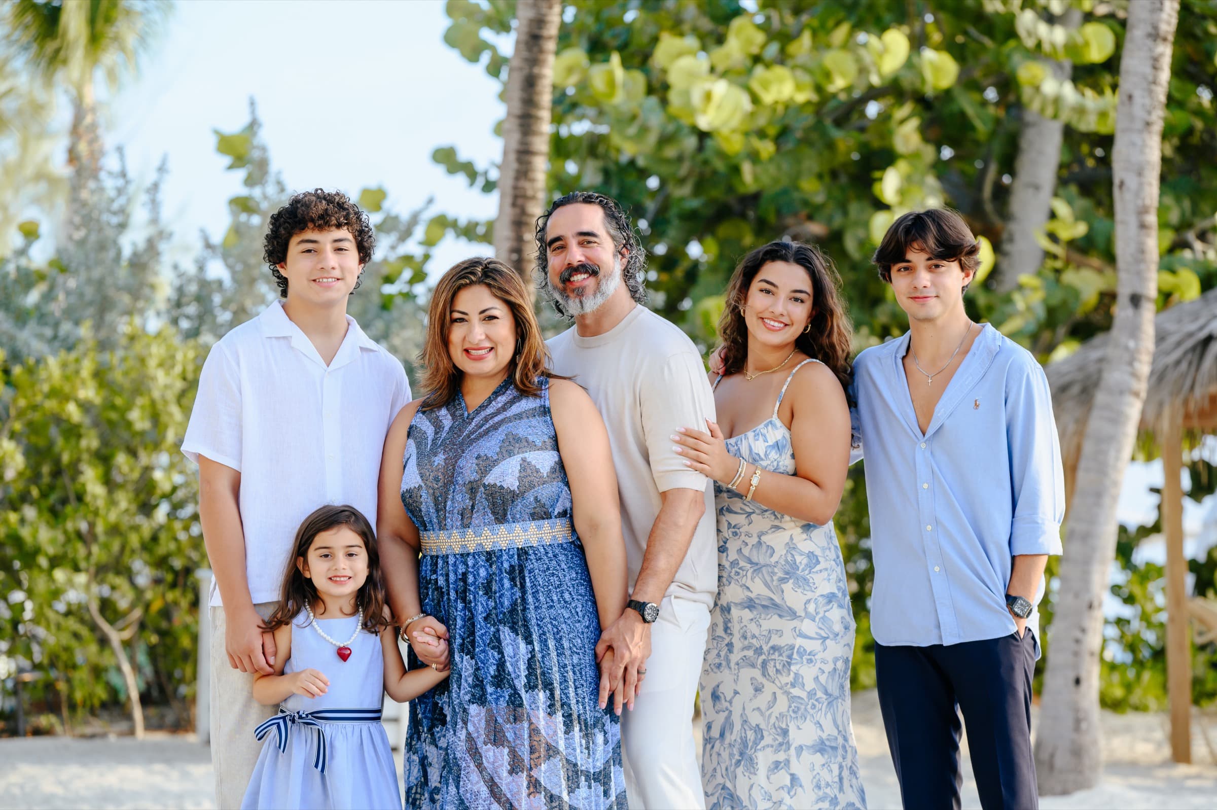 Manuel Suarez on the beach with his wife Gaby and their four children, everyone in blues and whites under the sea grape trees