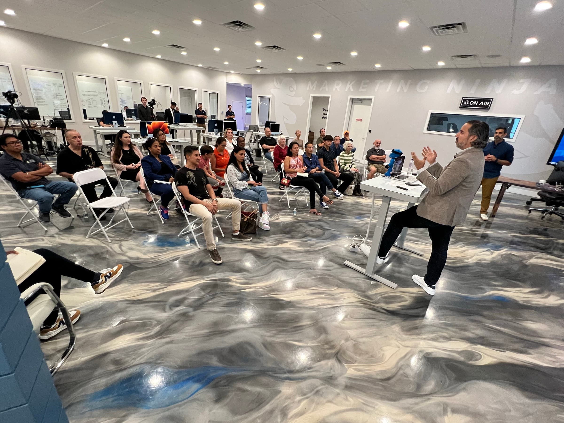 Manuel Suarez presents mid-gesture to an attentive seated audience inside the AGM Ninja Lab in Largo, Florida.