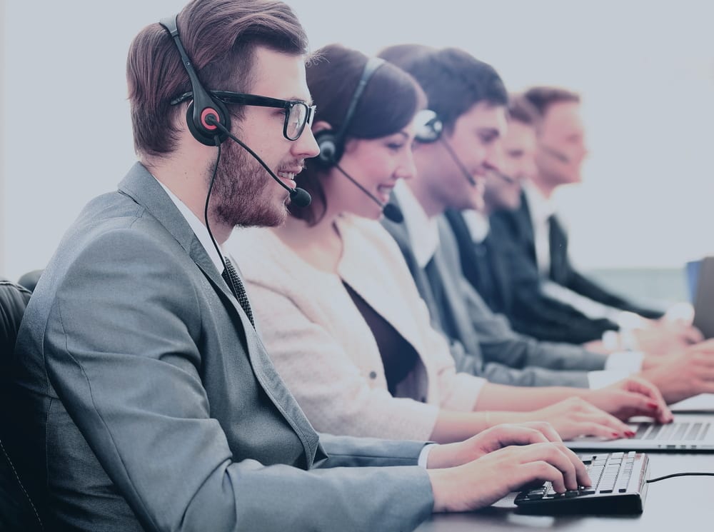 Attractive young man working in a call center with his colleagues