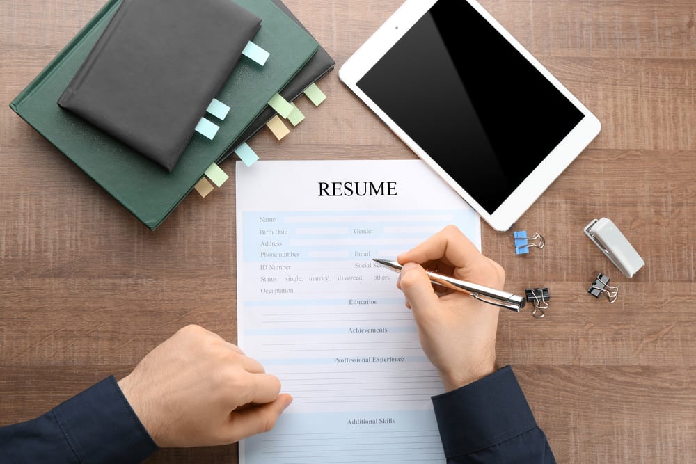 Woman filling in resume form at table. Job interview concept