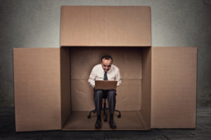 man working on laptop sitting on chair inside carton box