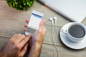 Smartphone text messaging against person using smart next to coffee mug at desk